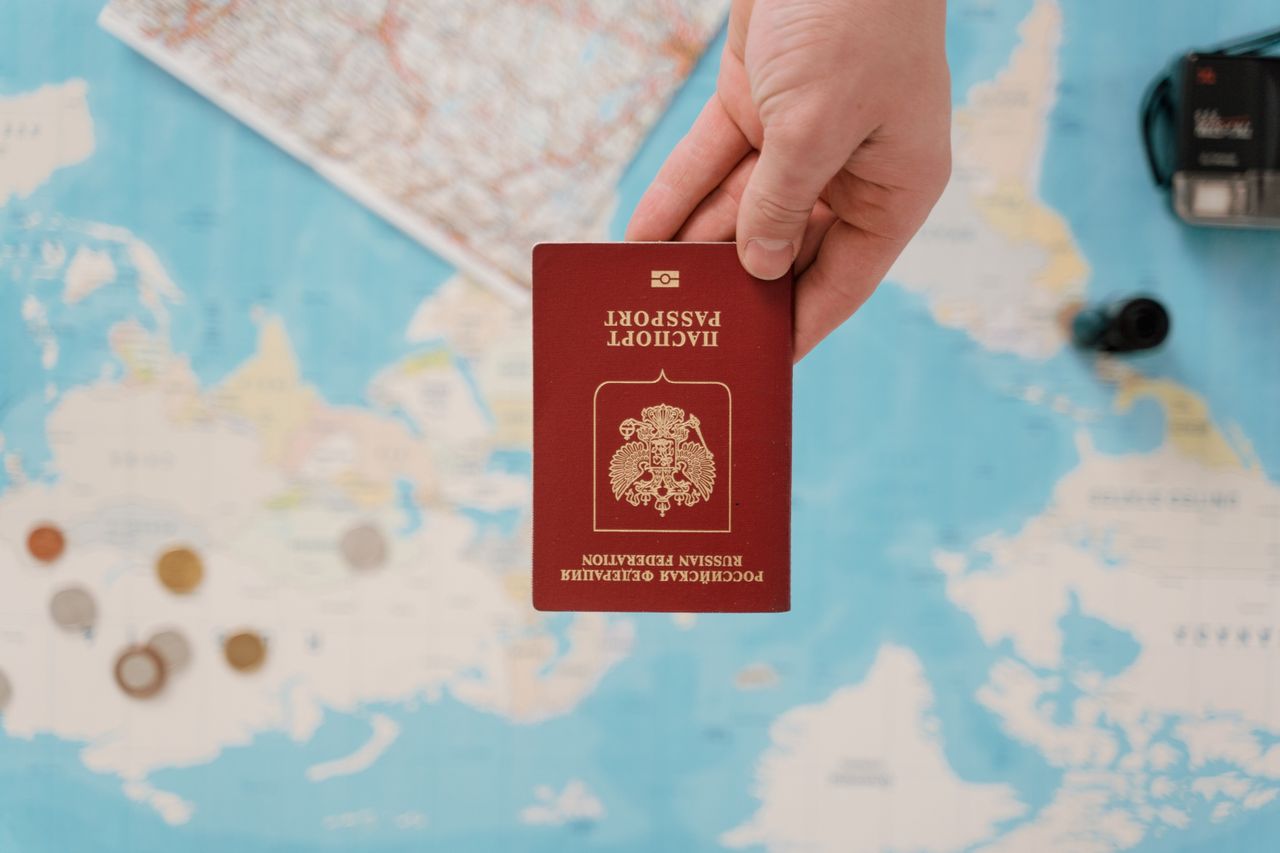 Mastering the First Impression: Your intriguing post title goes here A hand holding a Russian passport above a travel-themed map, capturing world travel concepts.